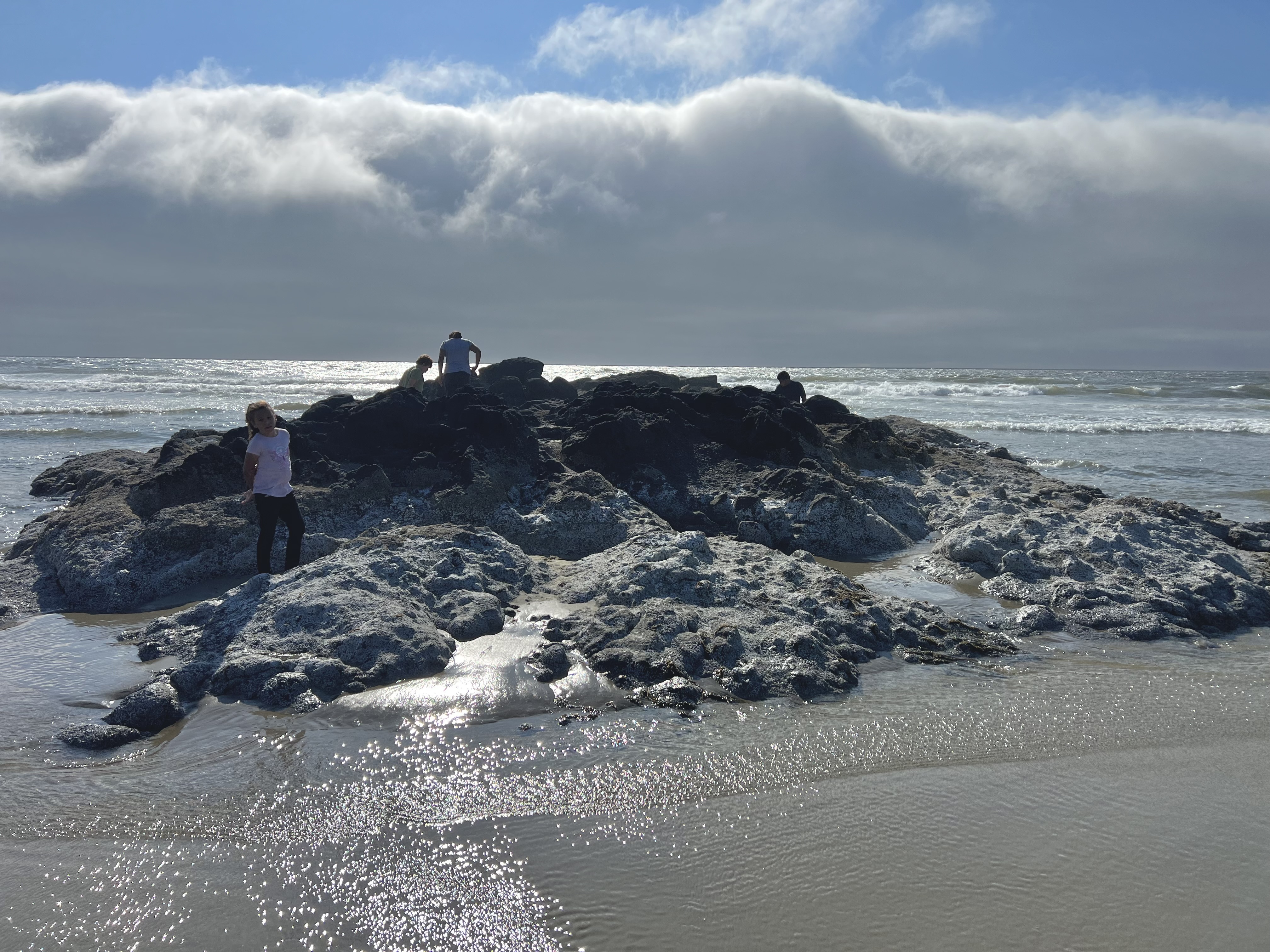 Photo outside of Florence Oregon of a beach with a giant rock and kids on it